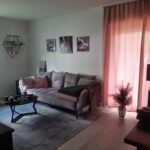 Wohnzimmer mit Zugang zur Loggia und zur Küche von der Diele aus betrachtet.