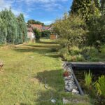 Der sehr große, sonnige Garten hinter dem Haus verfügt über einen Gartenteich und hat einen Zugang zur Garage