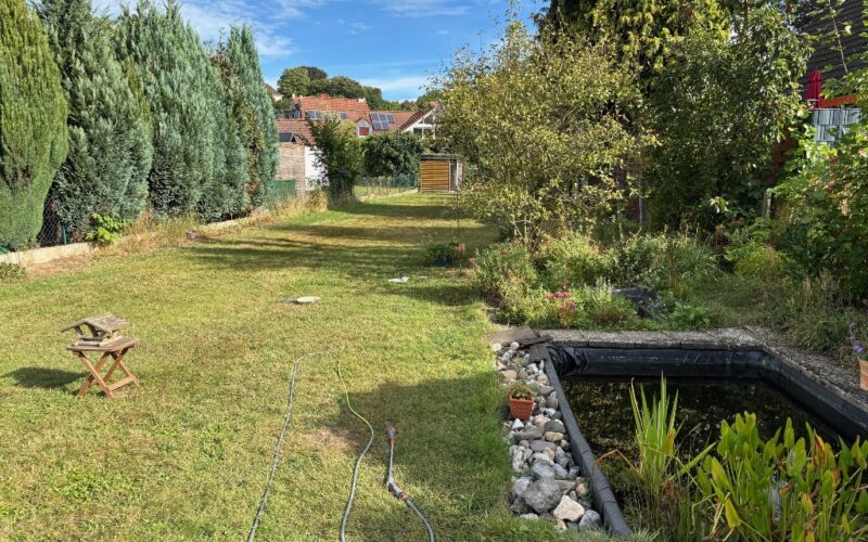 Der sehr große, sonnige Garten hinter dem Haus verfügt über einen Gartenteich und hat einen Zugang zur Garage
