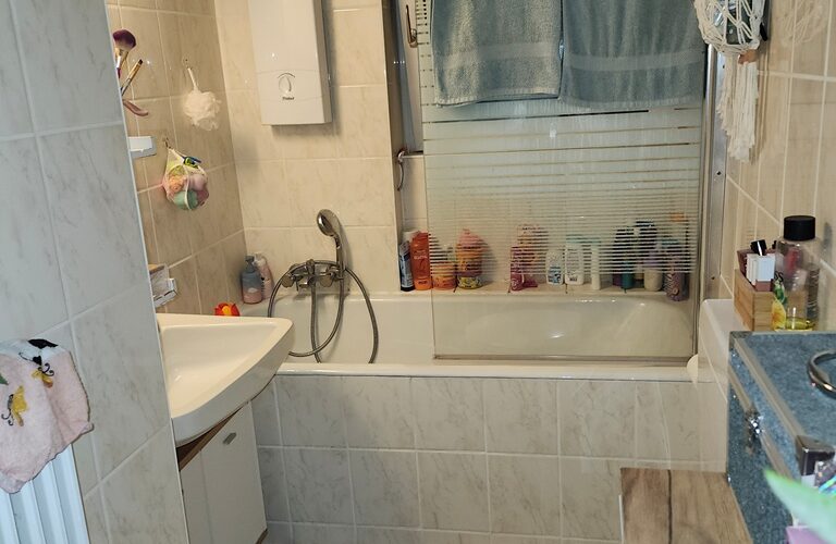 Tageslicht-Bad mit Badewanne, Waschtisch und WC im ersten Obergeschoß. der Fußboden ist gefliest.