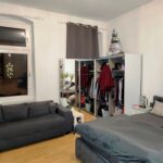 Das Kinderzimmer im ersten Obergeschoß hat zwei Fenster. Die Wände sind weiß gestrichen. Das Licht ist an. Die Fenter haben Vorhänge.