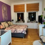 Ein geschmackvoll eingerichtetes Schlafzimmer im ersten Obergeschoß mit schöner Dekoration und einem Kinderbett.