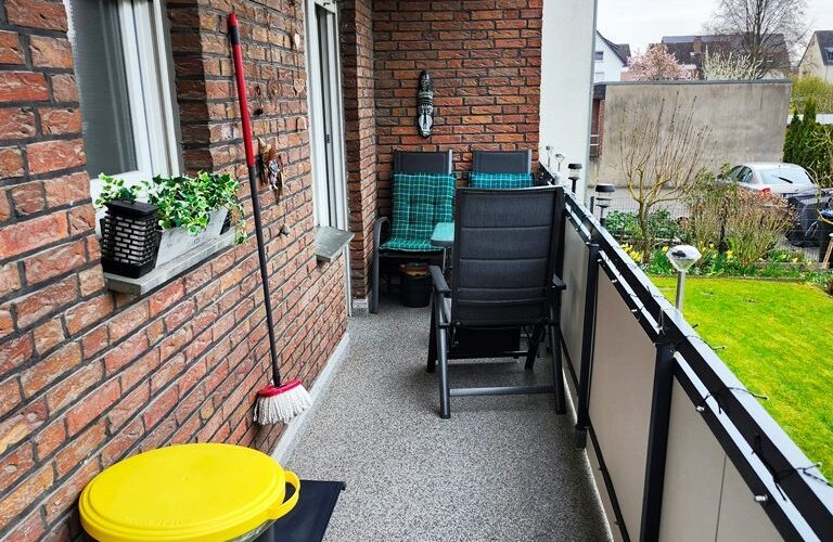 Auf dem Balkon seht eine Mülltonne mit gelbem Deckel