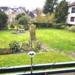 Vom Balkon sieht man die Terrasse im Garten und das Haus des Nachbarn