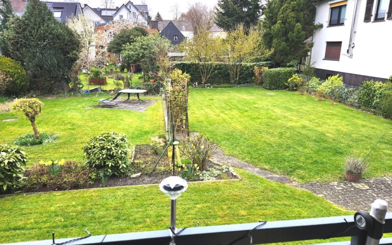 Vom Balkon sieht man die Terrasse im Garten und das Haus des Nachbarn
