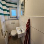 Gästetoilette mit modernen hellen Fliesen im Erdgeschoß des Wohnhauses am Waldrand in Hemer. Infos bei WZ-Immobilien