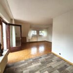 Blick durch das Wohnzimmer vom Balkon aus. Das Wohnzimmer hat unterschiedliche Fußbodenbeläge