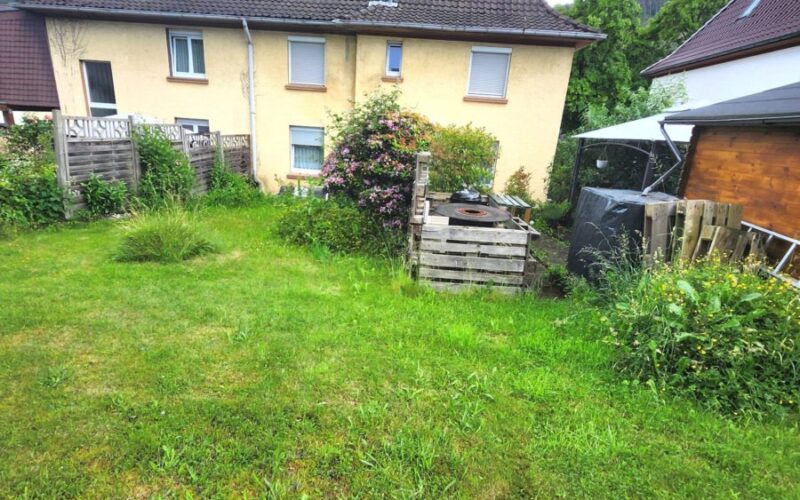 Großer garten hinter dem Haus in Nachrodt-Wiblingwerde. Auf dem Grundstück ist eine große Rasenfläche und ein Gartenhaus mit Grillplatz.