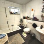 Bad mit Wanne, WC, und Waschtisch. Ein Fenster sorgt für Tageslicht