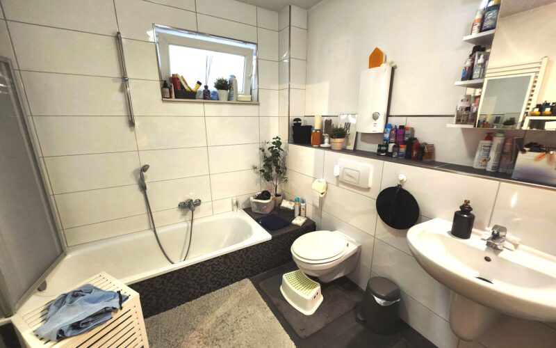 Bad mit Wanne, WC, und Waschtisch. Ein Fenster sorgt für Tageslicht