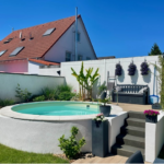 Poolanlage im Garten des Einfamilienhauses mit Treppe und erhabener Terrasse im Sonnenschein