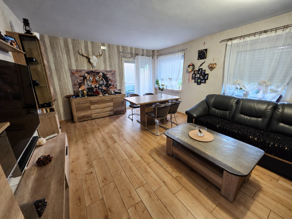 Wohnzimmer-Ansicht der Eigentumswohnung in Hemer mit Blickrichtung zum Balkon. Die Balkontüre steht auf.