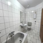 Bad mit Blick von der Wanne aus. Das Bad ist grau gefliest. Es gehört zur Mietwohnung im ersten Obergeschoß