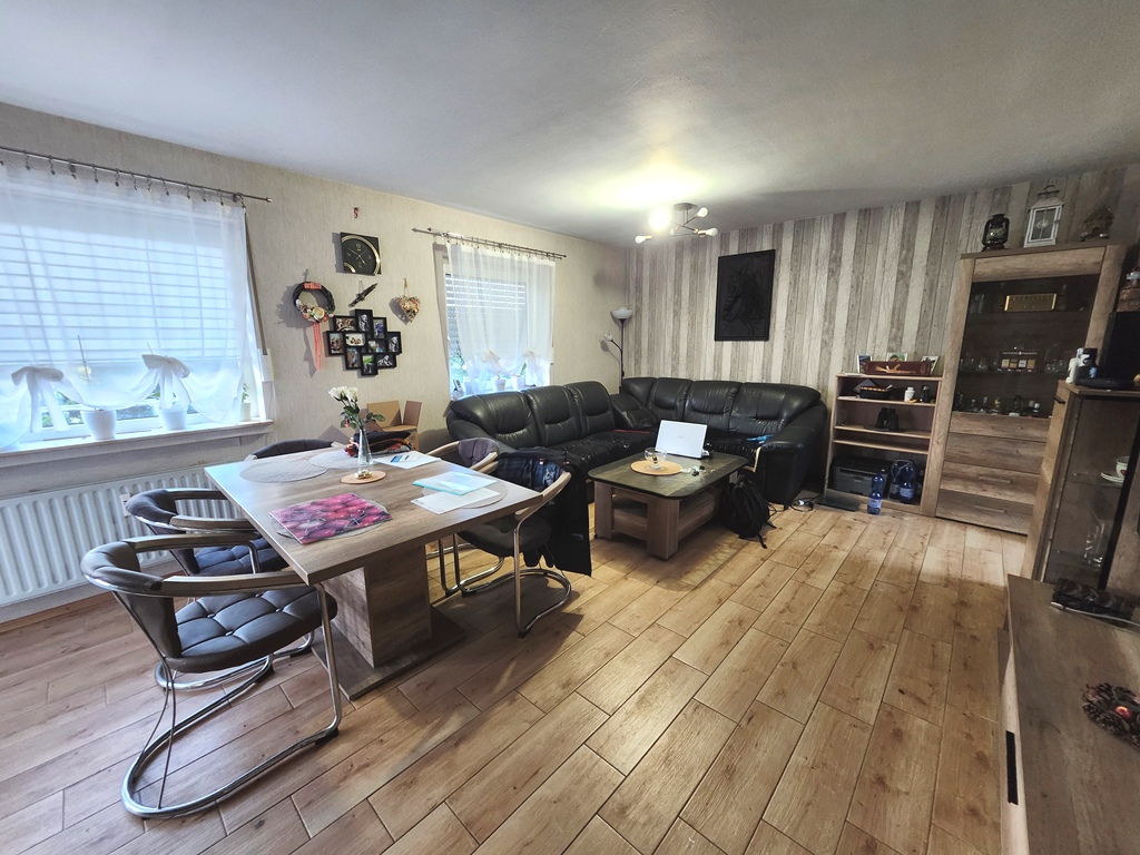 Wohnzimmer mit Essbereich und Zugang zum Balkon in der Eigentumswohnung im ersten Obergeschoß.